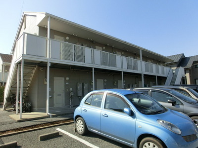 Building appearance. There is a parking lot at the entrance side.