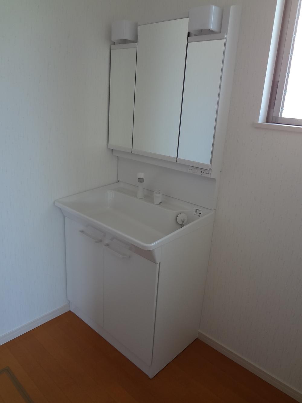 Wash basin, toilet. Behind it is housed in a three-sided mirror type