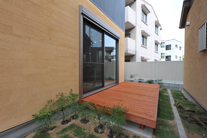 Building plan example (exterior photos). With a wood deck with green pillars