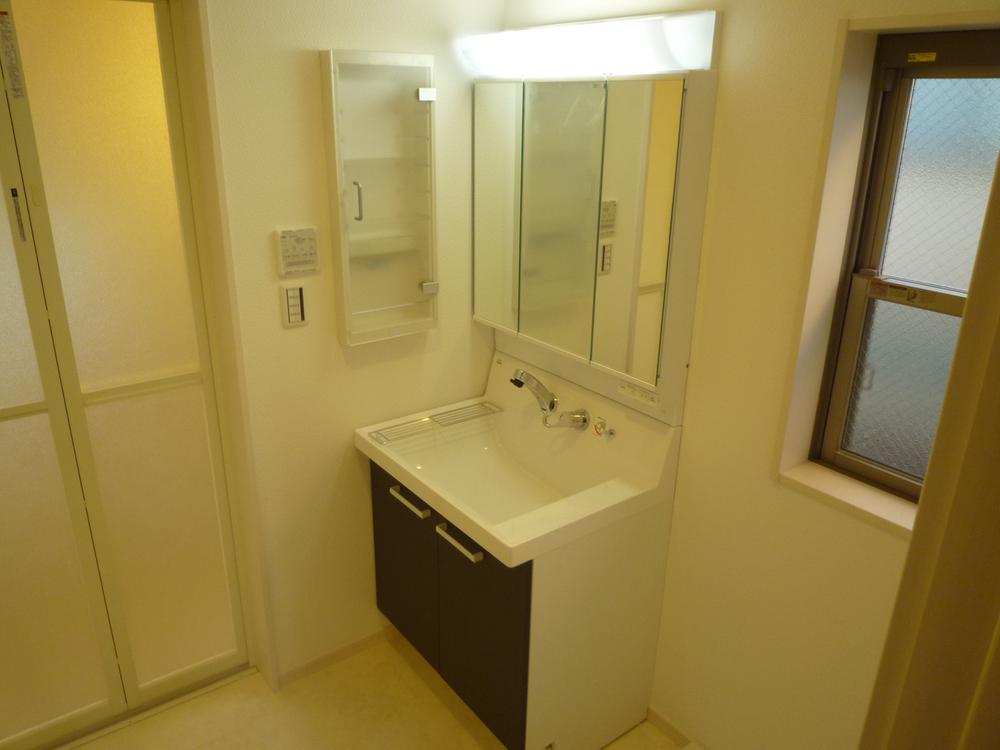 Wash basin, toilet. Complete with vanity up a notch by the three-sided mirror. 