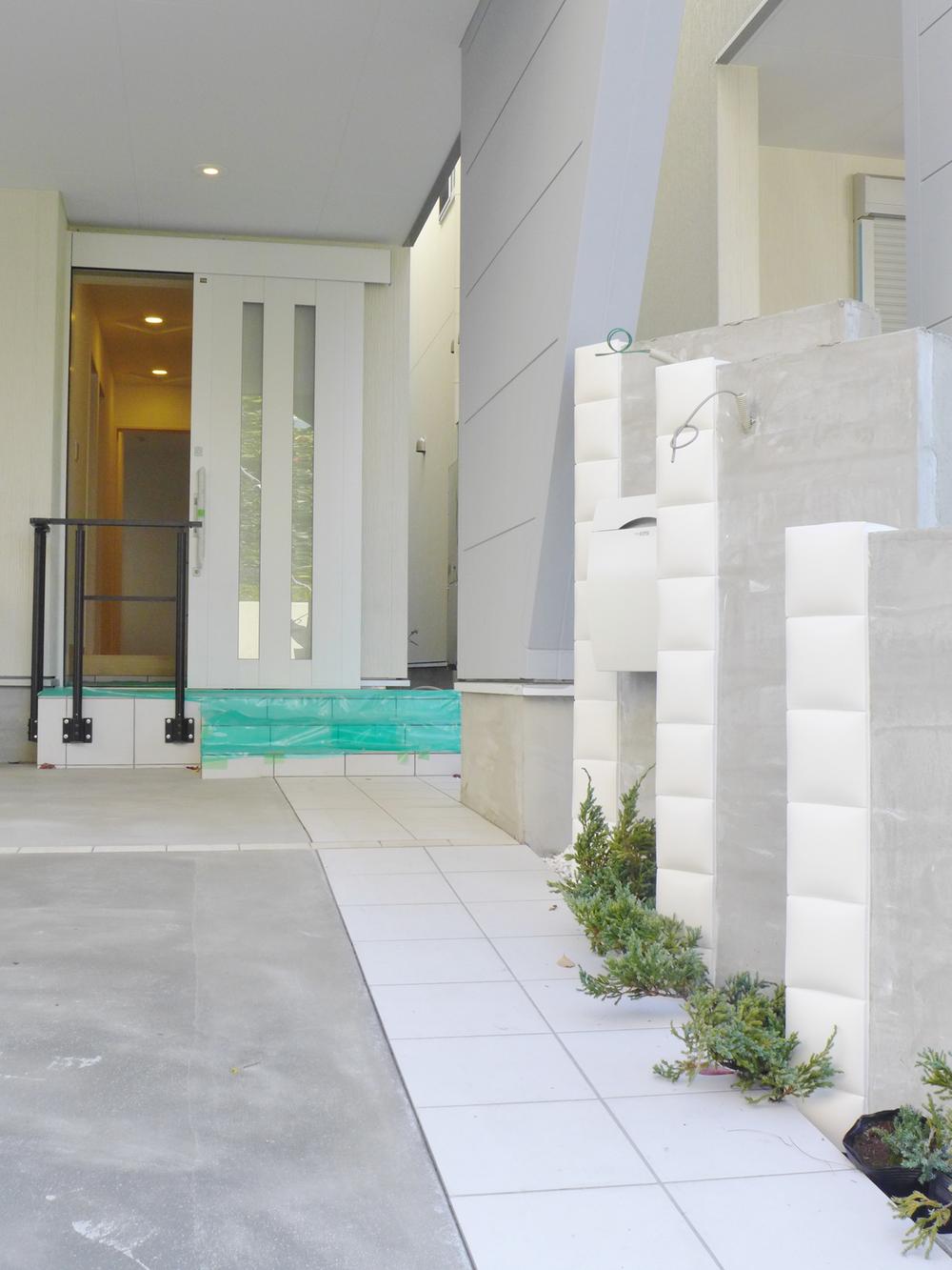 Local appearance photo. Approach to the entrance. Green of white brick and planting of accents exudes a sense of relief that came to our house. Entrance door is happy sliding to the elderly.