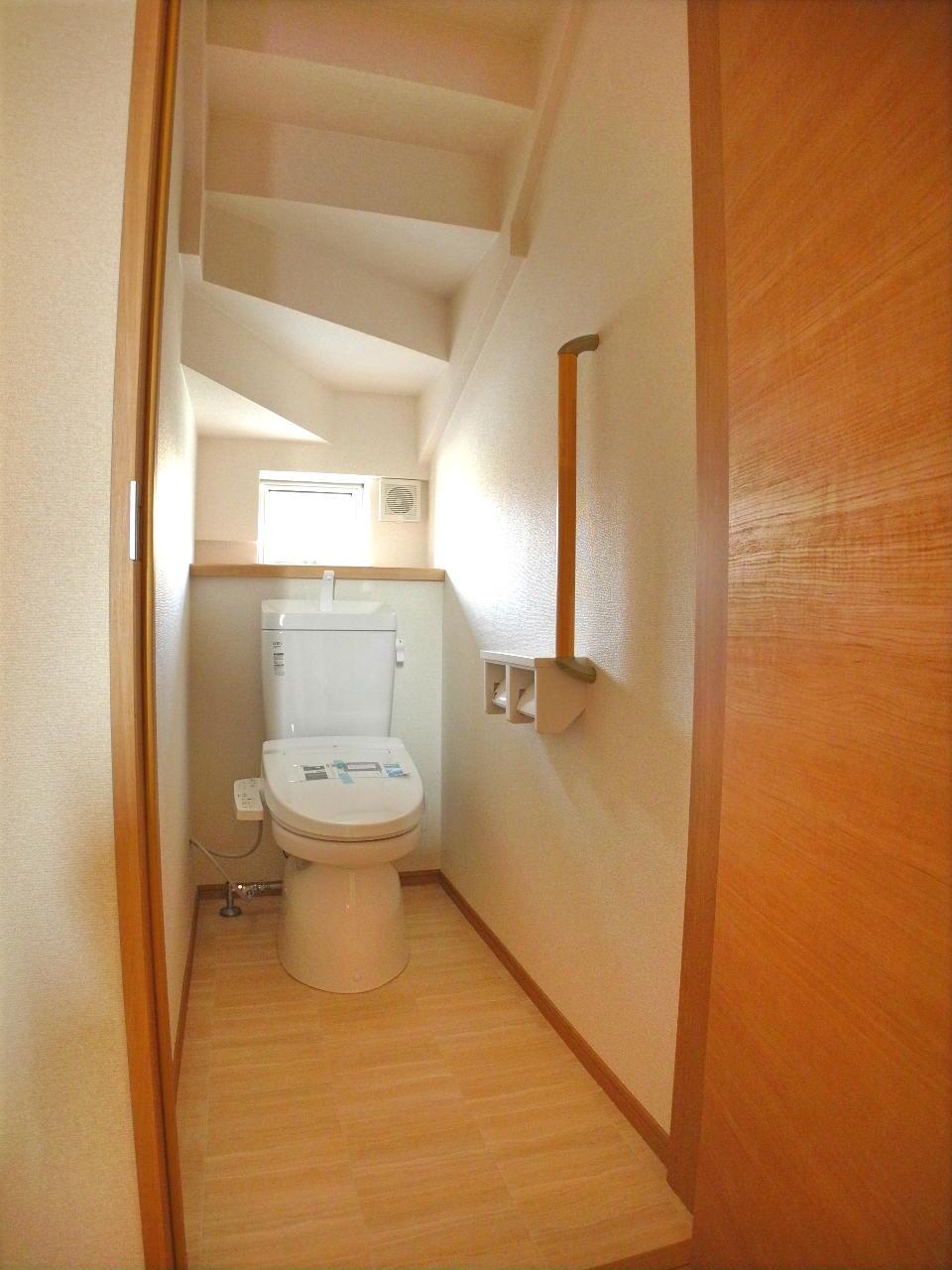 Toilet. Handrail is attached to the toilet. 