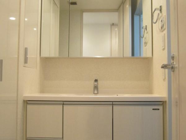 Wash basin, toilet. Wash basin with a woman in happy large three-sided mirror