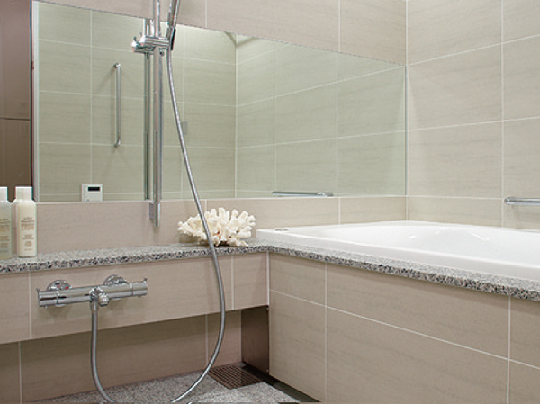 Bathing-wash room.  [Bathroom in pursuit of comfort] Tile panel of 300 × 600 square on the wall, Adopt a luxury high-quality natural stone on the floor. Joint has become to your easy-care super-clean joint. further, We have adopted a wide mirror to produce a spread of bathroom. Low-floor type of adoption Ya that was kept low straddle height of the tub, It has established a handrail.